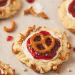 A closeup of a Strawberry Pretzel Pie Cookie decorated with creamy topping, jam, and a pretzel.