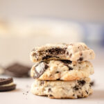 Three cookies in a stack with the top one with a bite removed.
