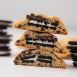 A stack of three Oreo stuffed chocolate chip cookies cut in half to reveal the Oreo cookie inside.