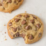 A large milk chocolate chip cookie with a bite removed.