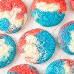 Red, white, and blue cookies on a crinkled page of parchment.