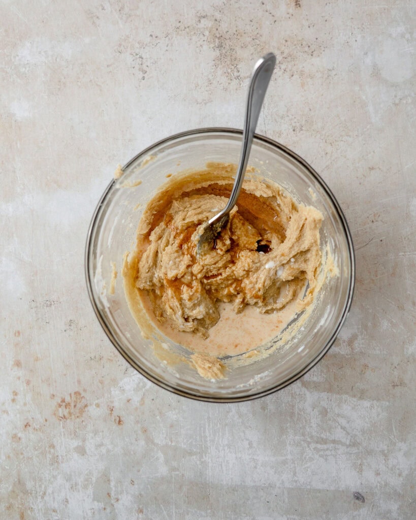 A bowl of butter, sugar, milk, and vanilla being mixed together.