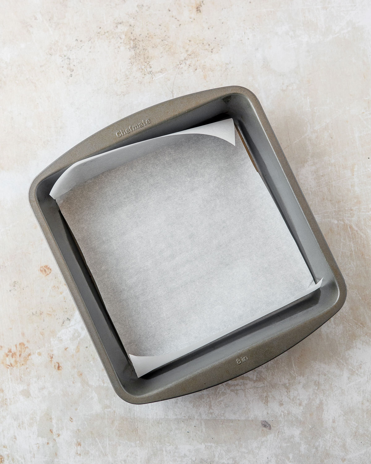 An 8x8 pan lined with parchment paper.