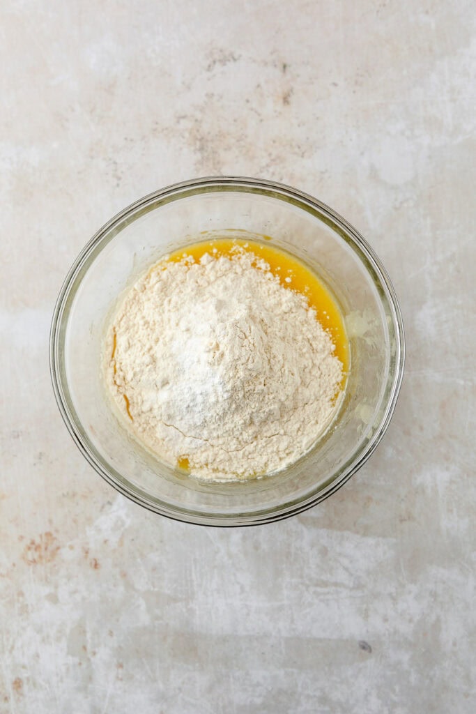 Wet and dry ingredients for cookie dough in a glass bowl.