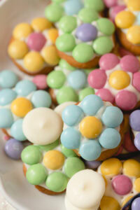 Small cookies decorated with white candy melts and pastel M&Ms in the shape of flowers.