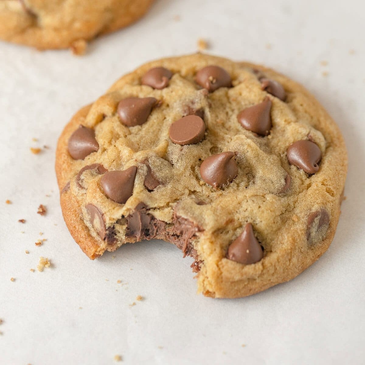 A large milk chocolate chip cookie with a bite removed.