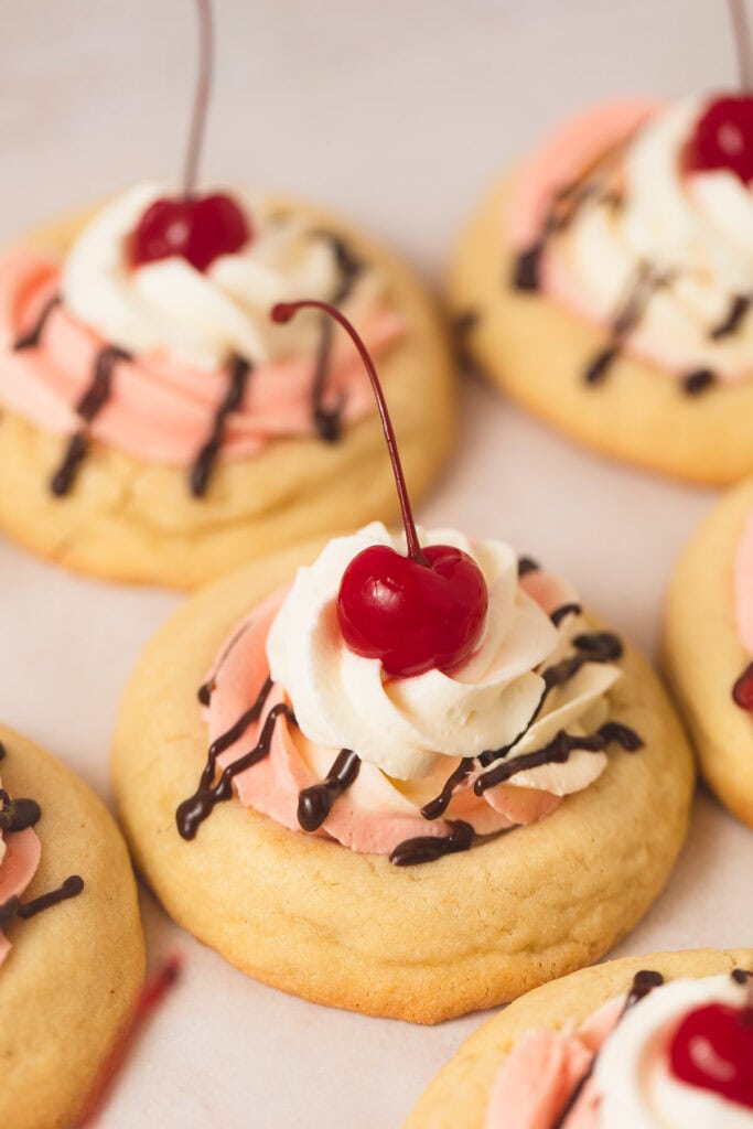 A Banana Split Cookie topped with strawberry and banana mousse, whipped cream, and a cherry on top.
