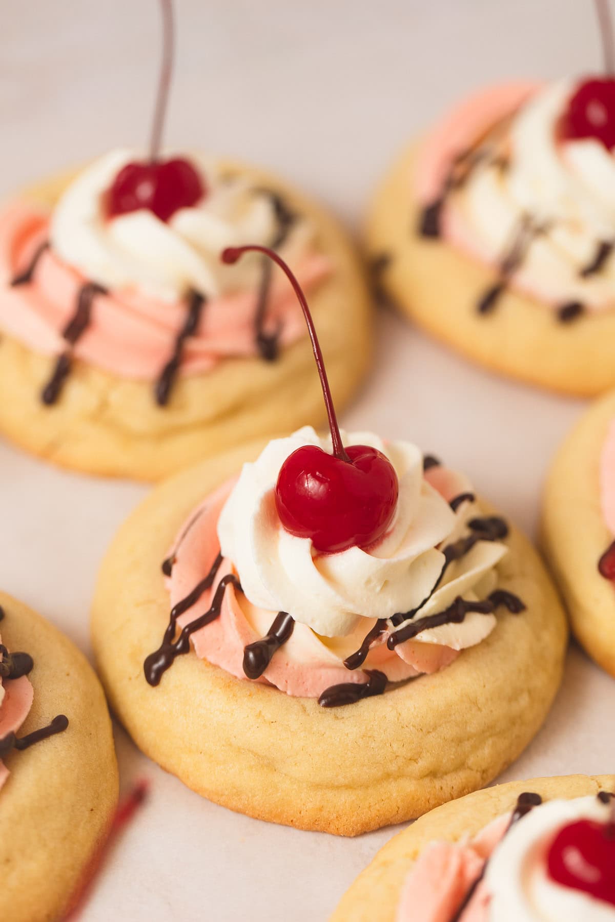 A Banana Split Cookie topped with strawberry and banana mousse, whipped cream, and a cherry on top.