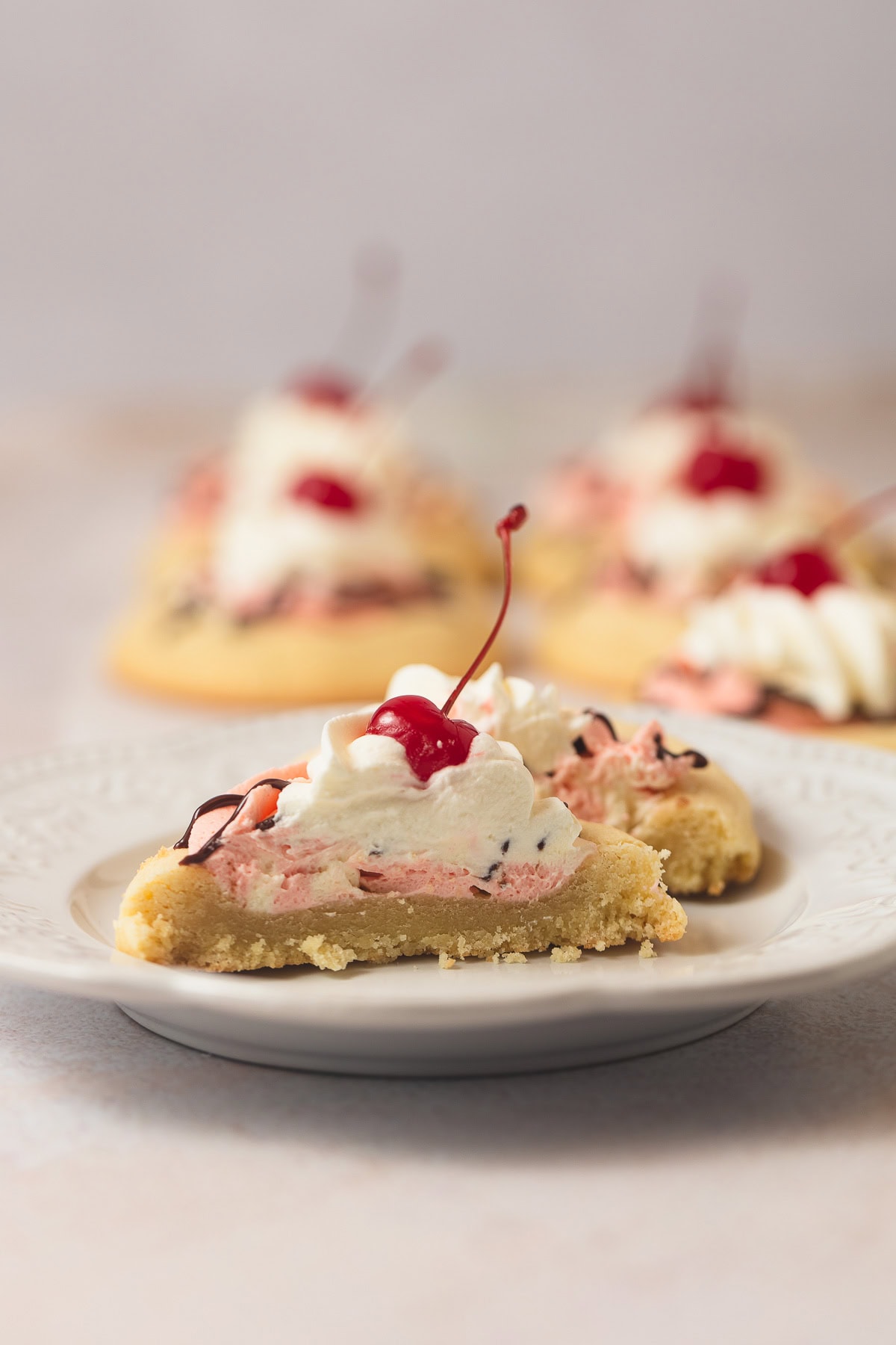 A halved banana split cookie with strawberry and banana mousse, whipped cream, and a cherry on top.