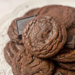 Brownie cookies on a plates with squares of chocolate alongside.