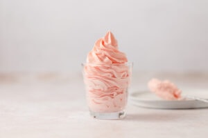 Piped pink strawberry mousse in a glass.
