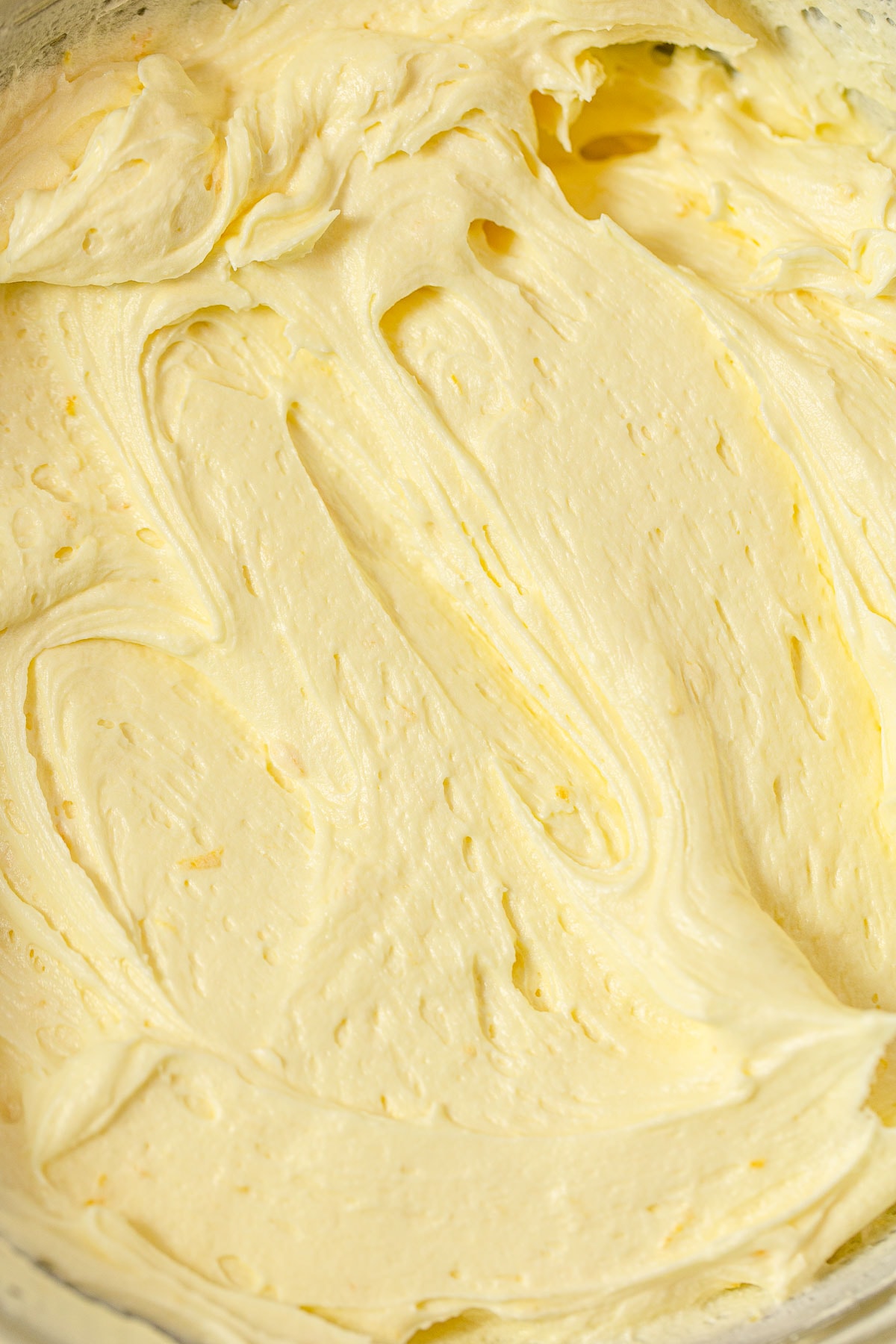A close-up texture image of light yellow lemon buttercream frosting.