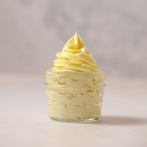 A mason jar filled with piped light yellow lemon frosting.
