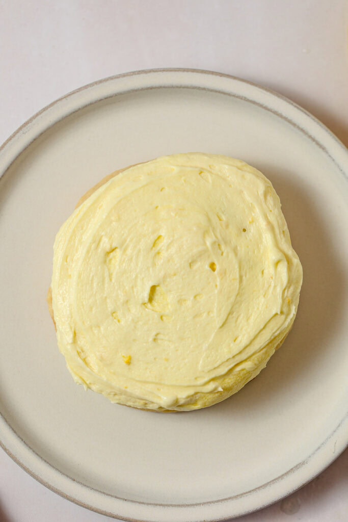 A sugar cookie topped with yellow lemon buttercream.