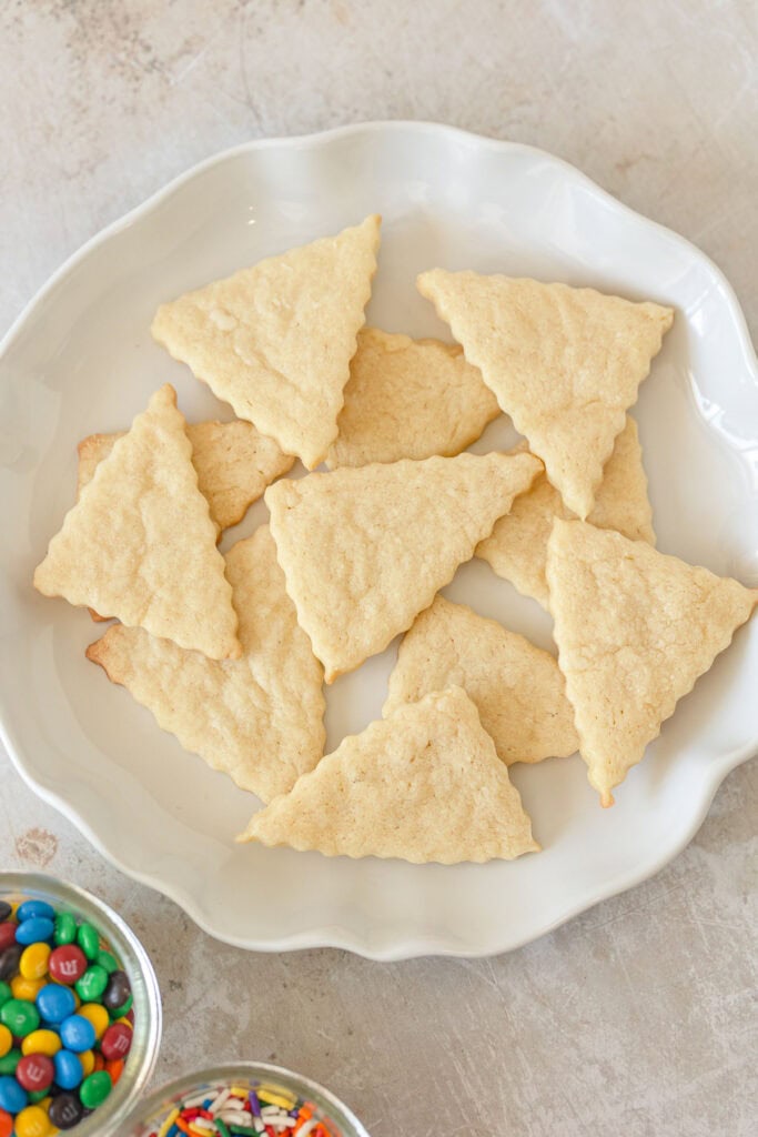 A plate of triangle-shaped sugar cookies with ruffled edges.