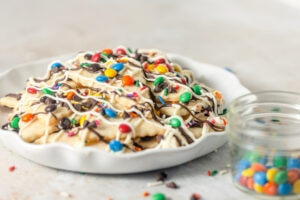 A large plate with sugar cookie "nachos" topped with drizzles of chocolate, mini M&Ms, and sprinkles.