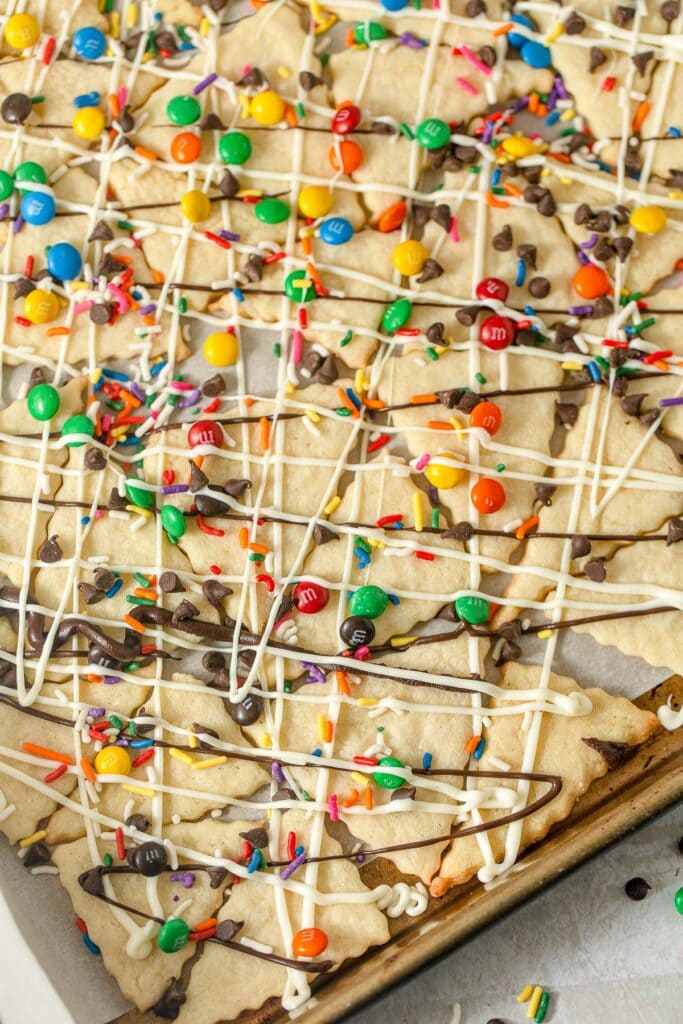 A tray of triangle sugar cookies "nachos" topped with drizzles of chocolate and small candies.