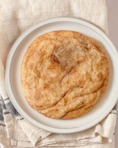 A large snickerdoodle cookie on a rustic plate.