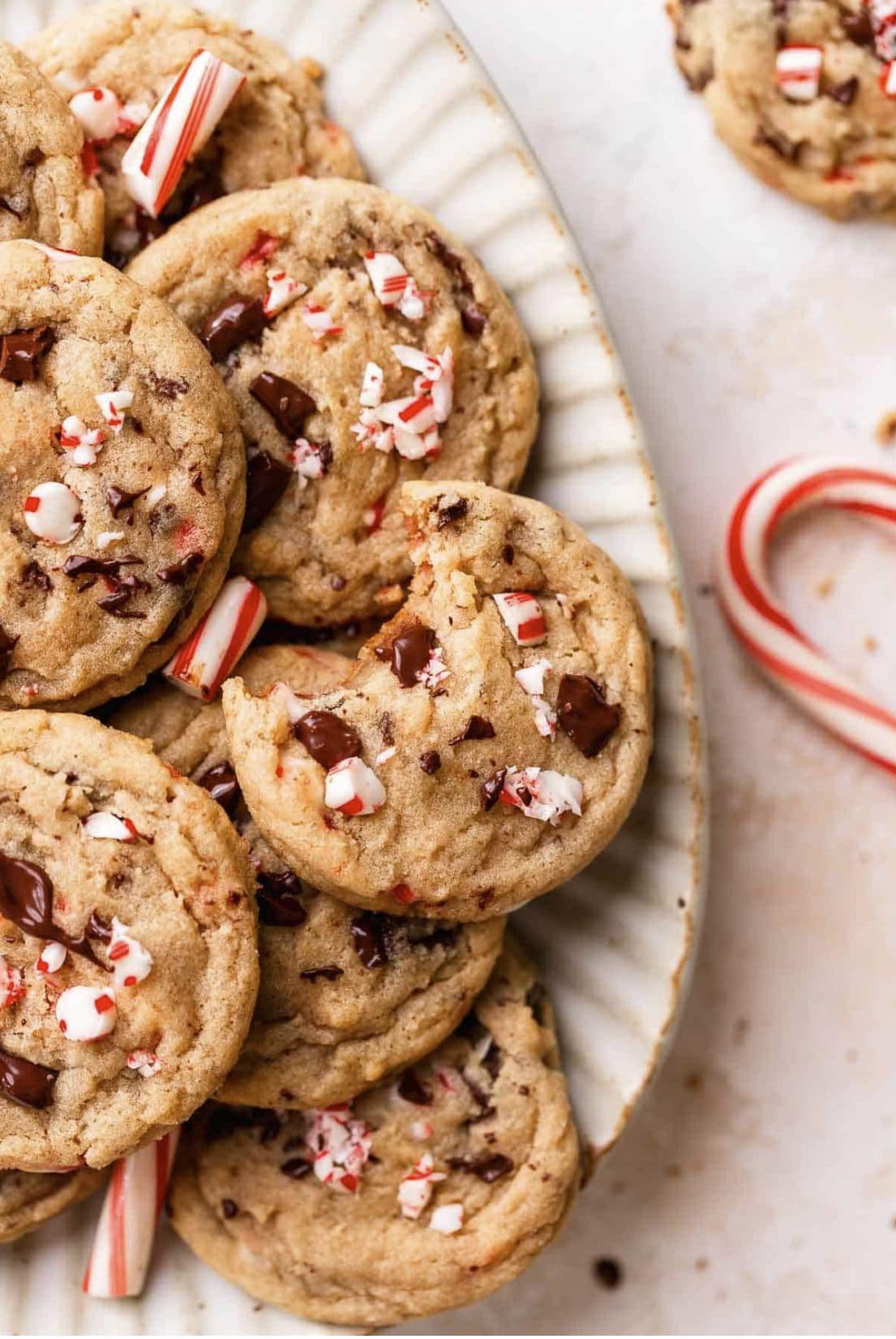 Chocolate chip cookies studded with peppermint pieces arranged on a rustic plate.