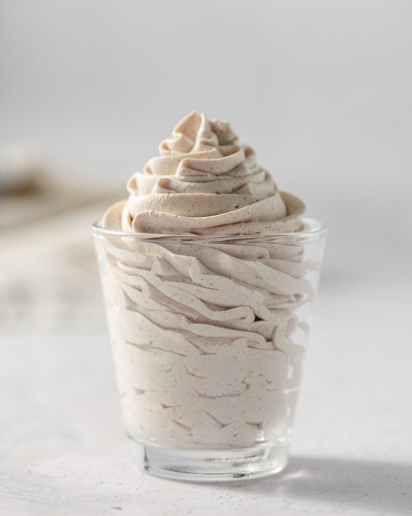 Swirls of piped cinnamon whipped cream in a small glass.