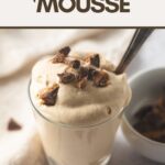 A glass filled with light brown peanut butter mousse topped with chopped peanut butter cups, with the words, "Peanut Butter Mousse".