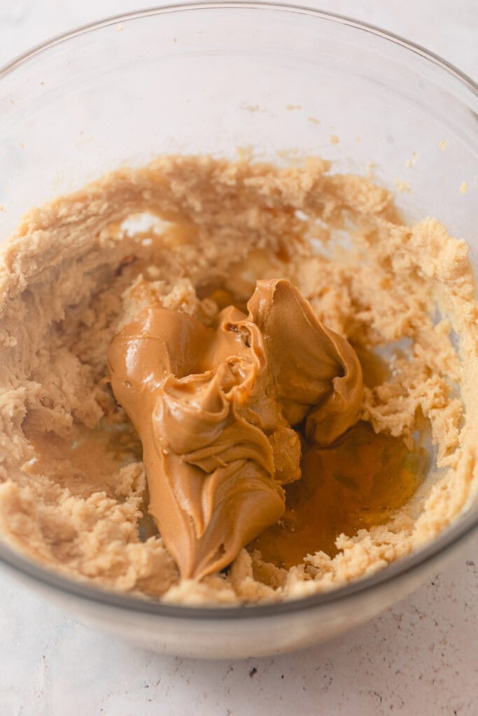 A bowl of creamed butter and sugar with peanut butter and an egg added.