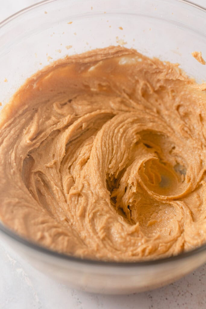 A bowl of creamed butter, sugar, egg, peanut butter, and vanilla extract mixed together until smooth.