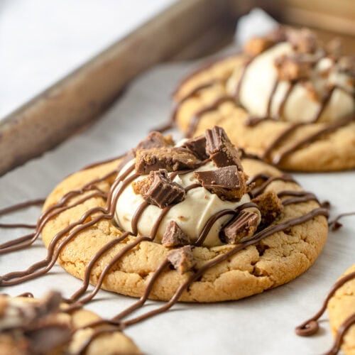 Peanut butter cookies topped with a scoop of peanut butter mousse, drizzles of milk chocolate and pieces of crushed peanut butter cups.