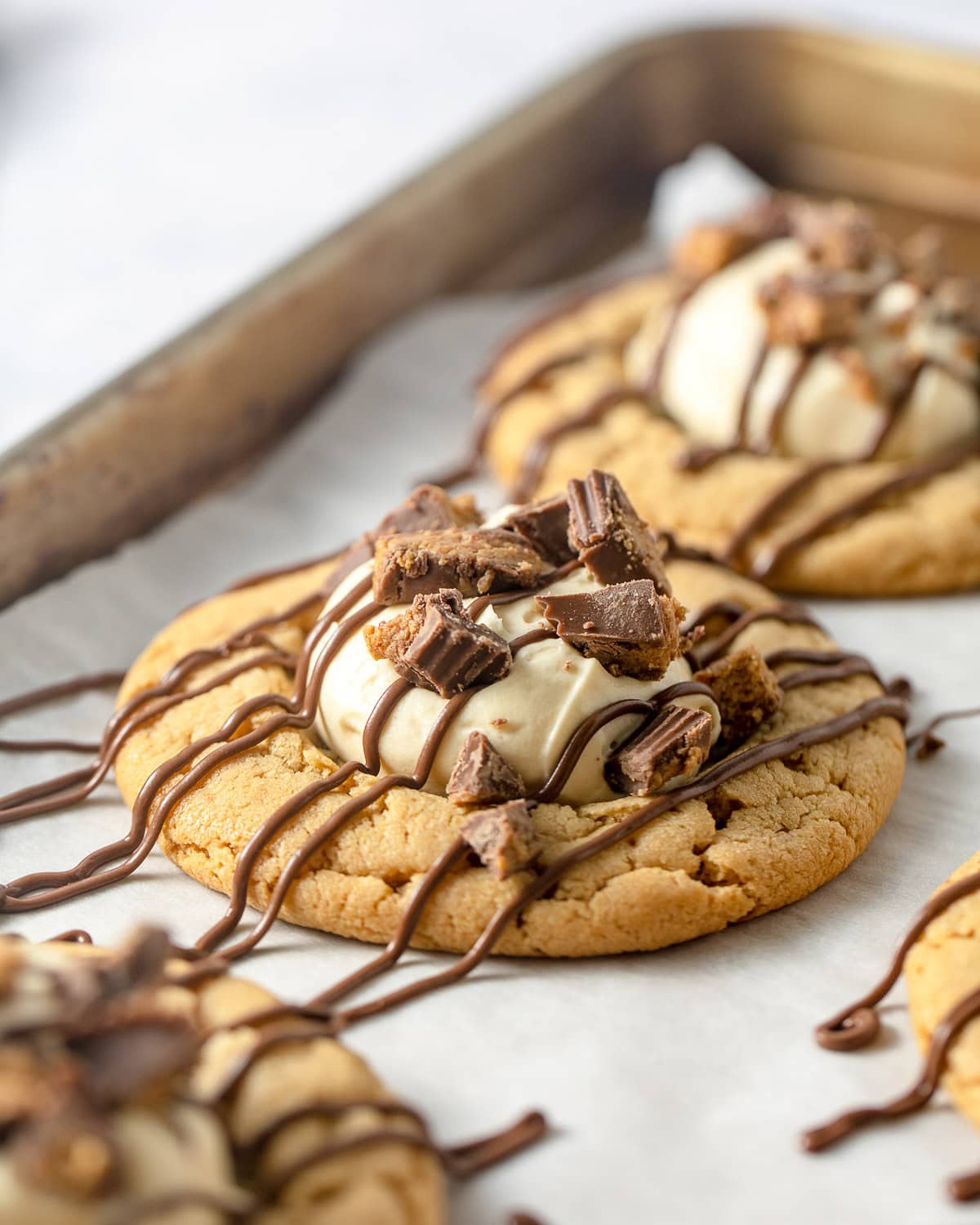 Peanut butter cookies topped with a scoop of peanut butter mousse, drizzles of milk chocolate and pieces of crushed peanut butter cups.