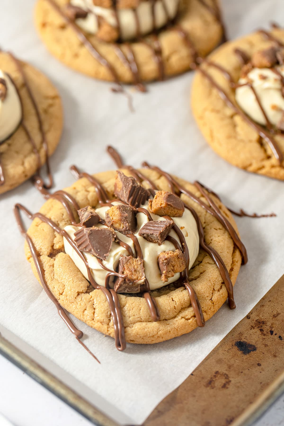 Peanut butter cookies topped with a scoop of peanut butter mousse, drizzles of milk chocolate and pieces of crushed peanut butter cups.