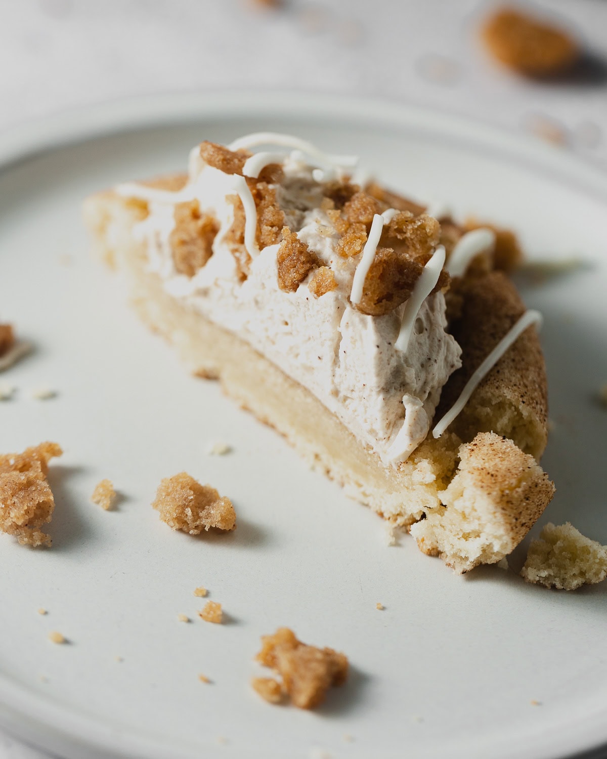 A snickerdoodle cookie filled with cinnamon whipped cream and topped with streusel and drizzles of white chocolate and cut in half.