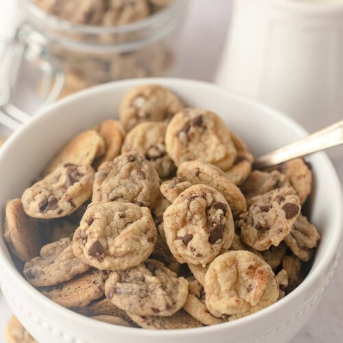 A cereal bowl filled with mini chocolate chip cookies and a spoon.