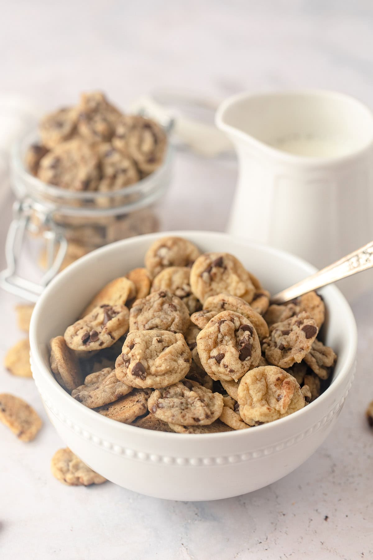 A white cereal bowl filled with mini chocolate chip cookies.
