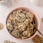A pink bowl filled with mini cookies & cream cookie cereal and a spoon.