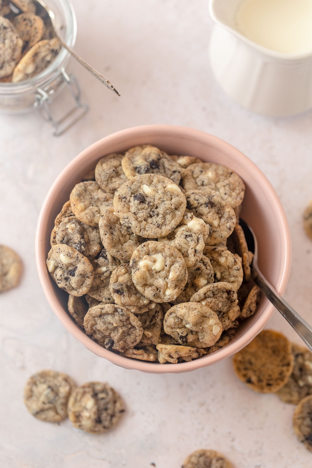 A pink bowl filled with mini cookies & cream cookie cereal and a spoon.