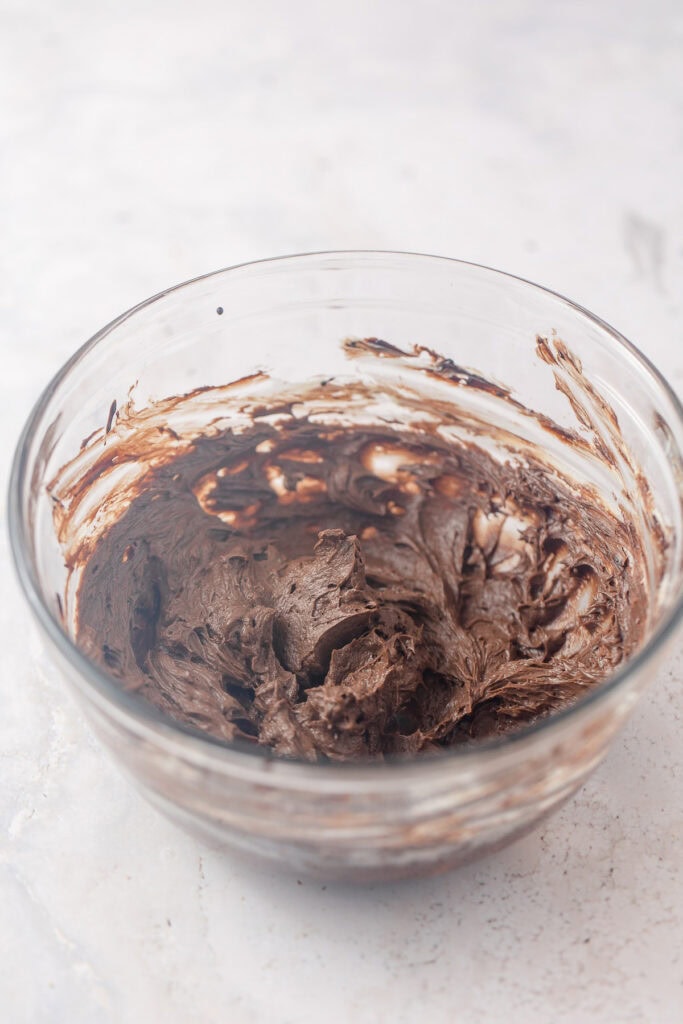 A glass bowl filled with thick "hot chocolate" frosting before adding the powdered sugar.
