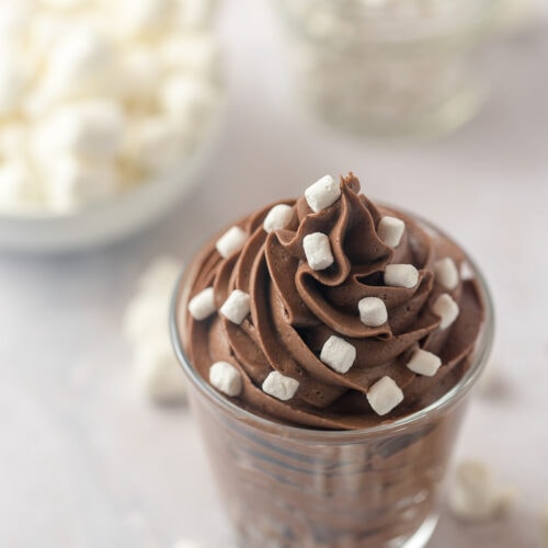 Piped chocolate buttercream in a glass jar topped with very tiny marshmallows.