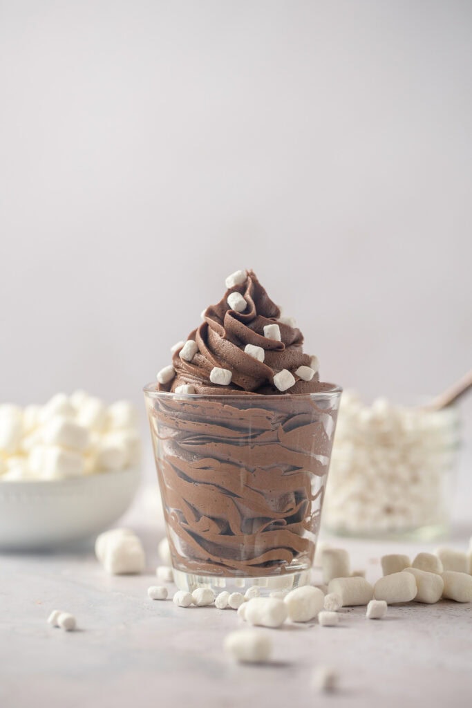 Piped chocolate buttercream in a glass jar topped with very tiny marshmallows.