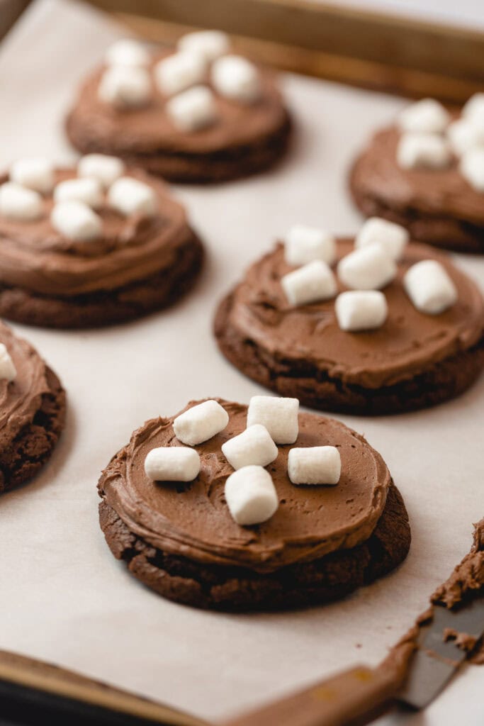 A tray of chocolate cookies frosted with chocolate frosting and mini marshmallows.
