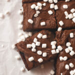 A pan of frosted brownies decorated with very tiny marshmallows and cut into squares.