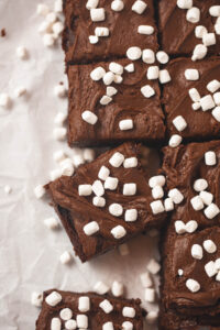 A pan of frosted brownies decorated with very tiny marshmallows and cut into squares.