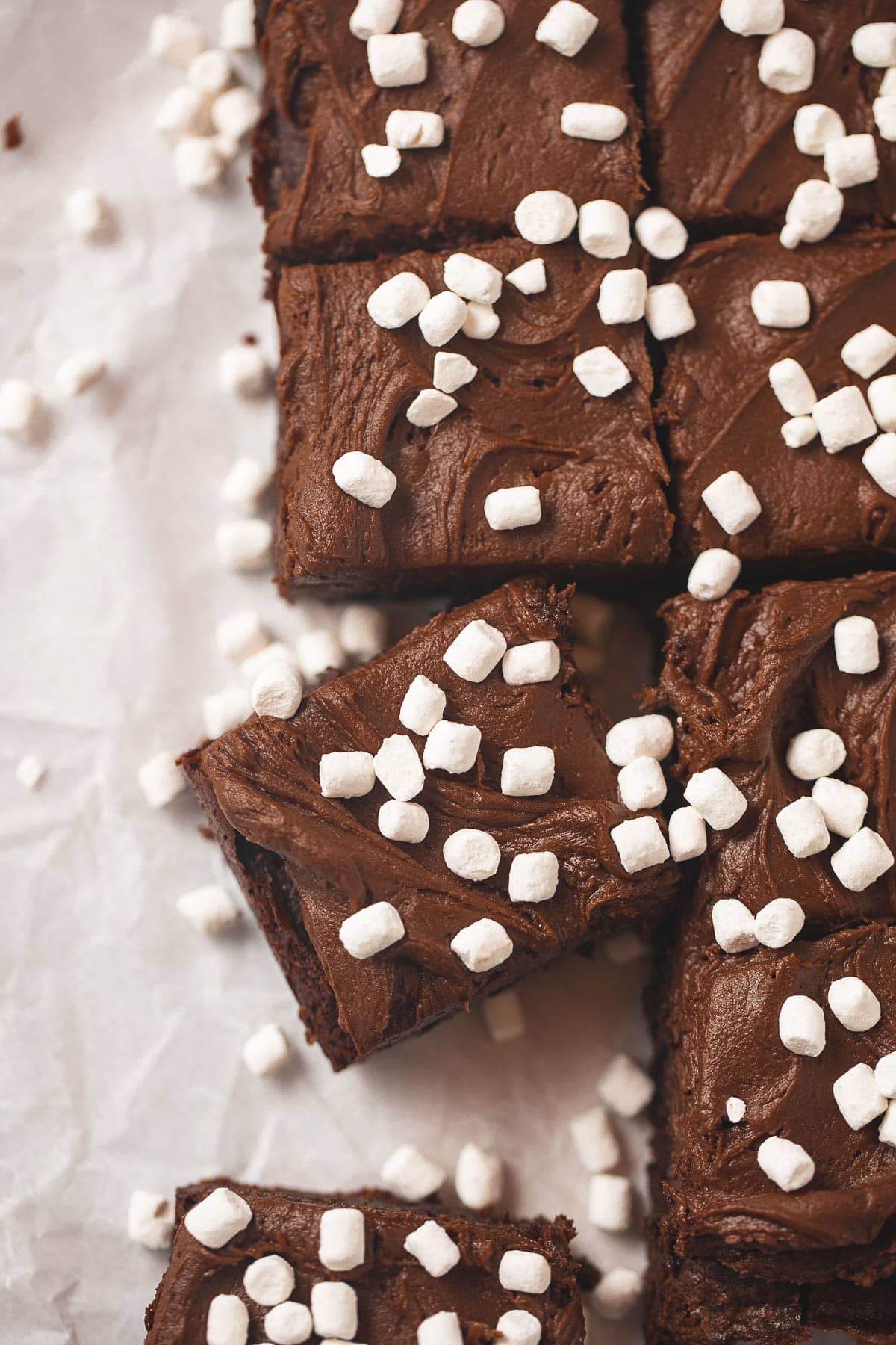 A pan of frosted brownies decorated with very tiny marshmallows and cut into squares.