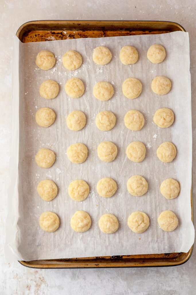 A tray of light yellow mini lemon cookies fresh from the oven.
