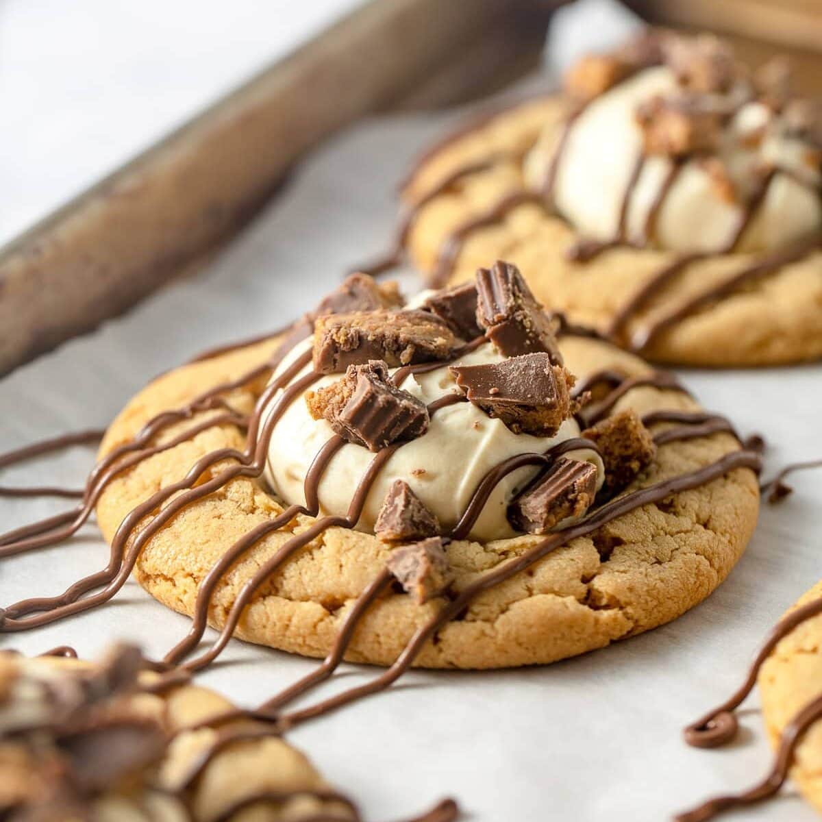 Peanut butter cookies topped with a scoop of peanut butter mousse, drizzles of milk chocolate and pieces of crushed peanut butter cups.